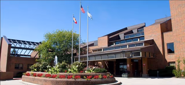 Front view of Cottingham Retirement Community building with flags and landscaped entrance.