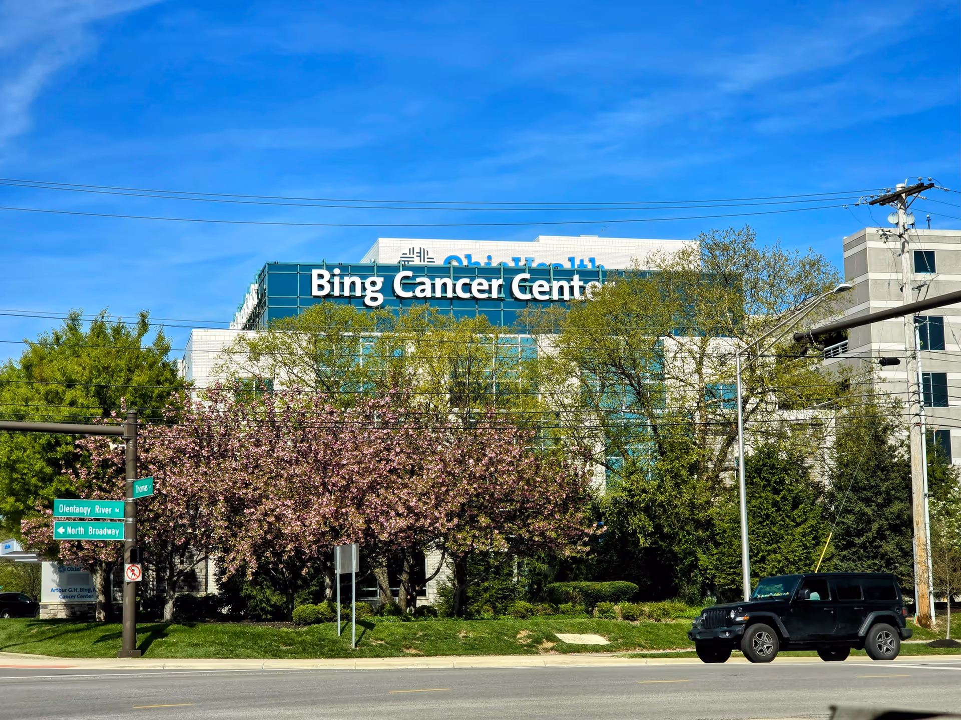 Exterior view of Bing Cancer Center building with trees and a parked SUV.
