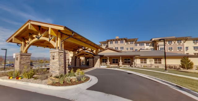 Exterior view of Wind Crest Senior Living Community entrance with a covered drive and stone pillars
