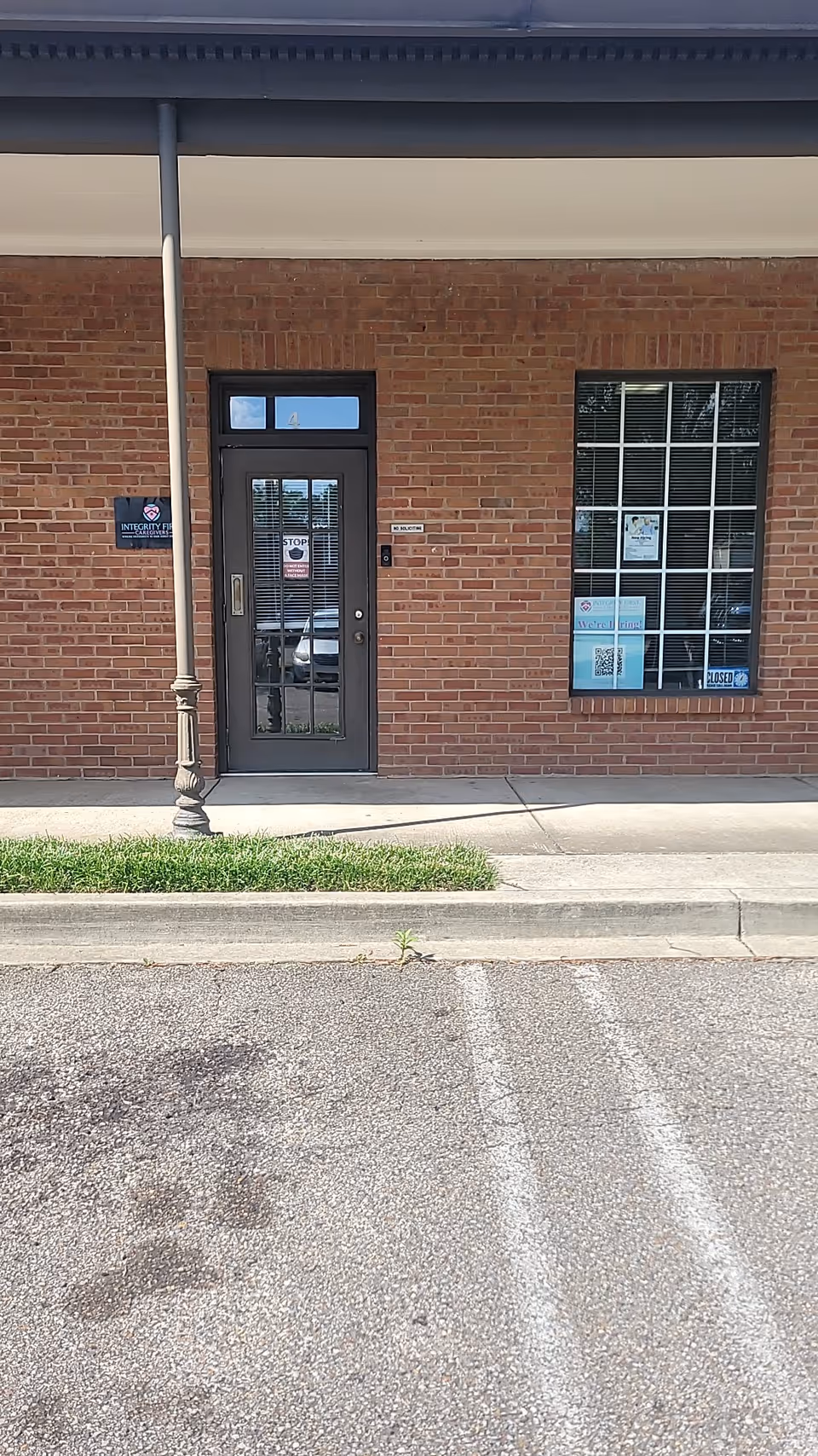 Brick exterior with glass door entrance, large window, and Integrity First Caregivers sign.
