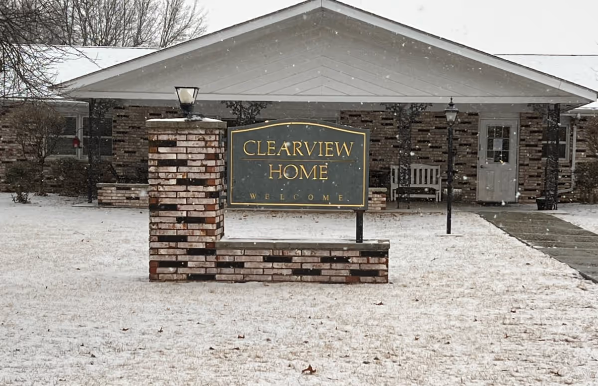 Snowy front of Clearview Home building with sign and brick entrance.