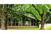 Front view of a glass-windowed senior living facility framed by trees.