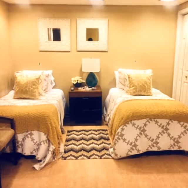 Two twin beds with a nightstand between, beige decor, and chevron rug.