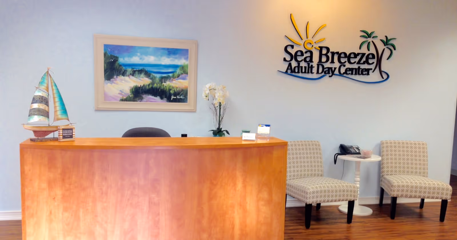 Reception desk in Sea Breeze Adult Day Center lobby with two cream chairs.