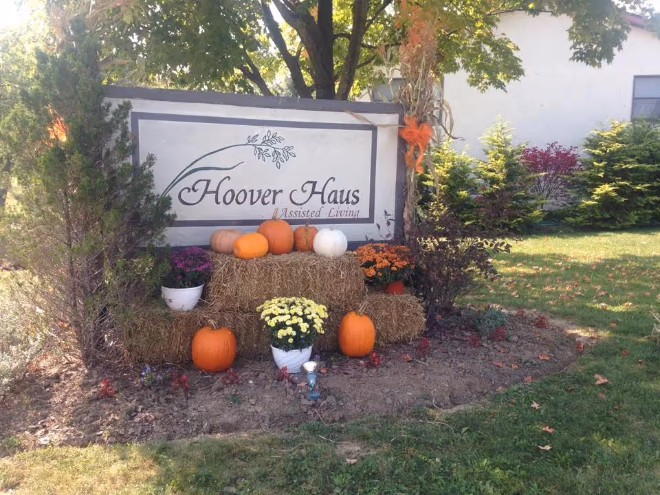 Hoover Haus Assisted Living sign framed by pumpkins and hay bales outside.