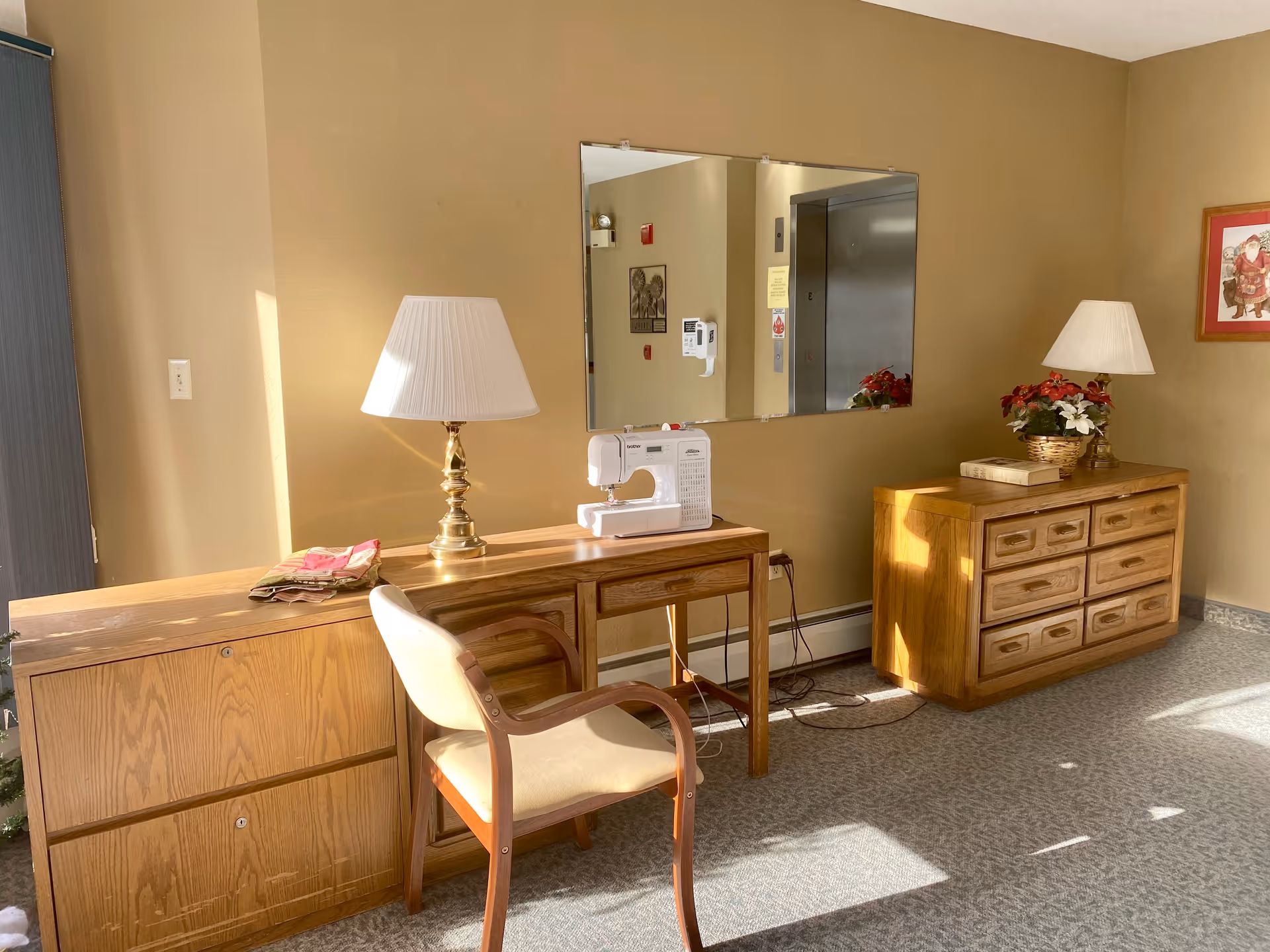 A warm lobby area with wooden desks, lamps, a mirror, and a sewing machine.