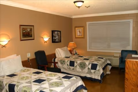 Two twin beds with patchwork quilts in a warmly lit resident bedroom.