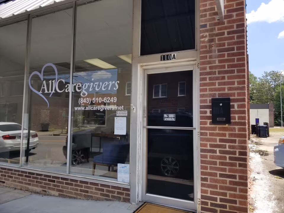 Front exterior of AllCaregivers storefront with glass windows and brick facade.