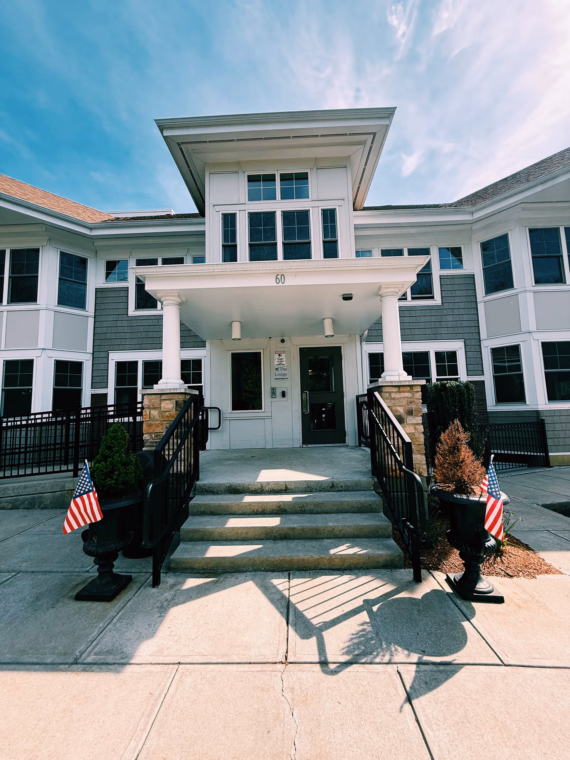 Front entrance of Golden Pond Assisted Living with steps, columns, and American flags.
