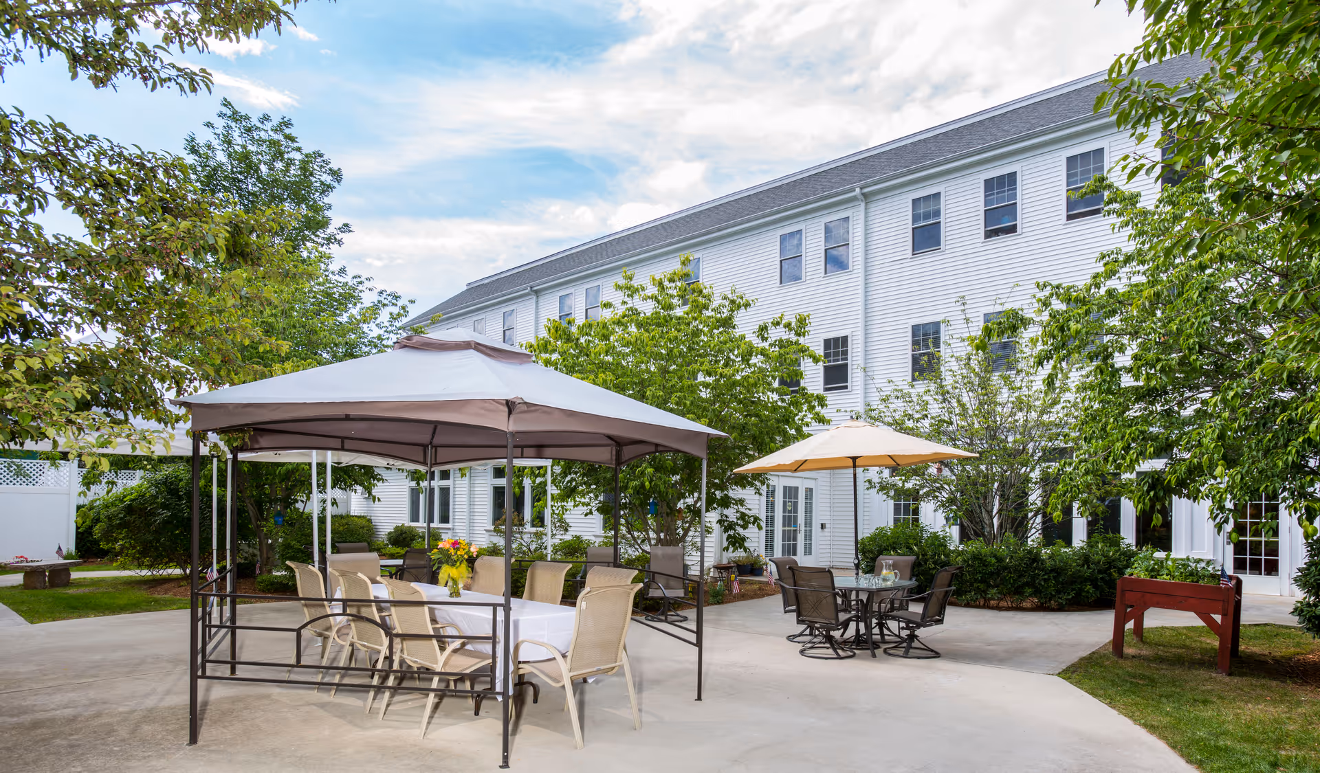 Outdoor courtyard at Benchmark Senior Living at Robbins Brook with tables and umbrellas.