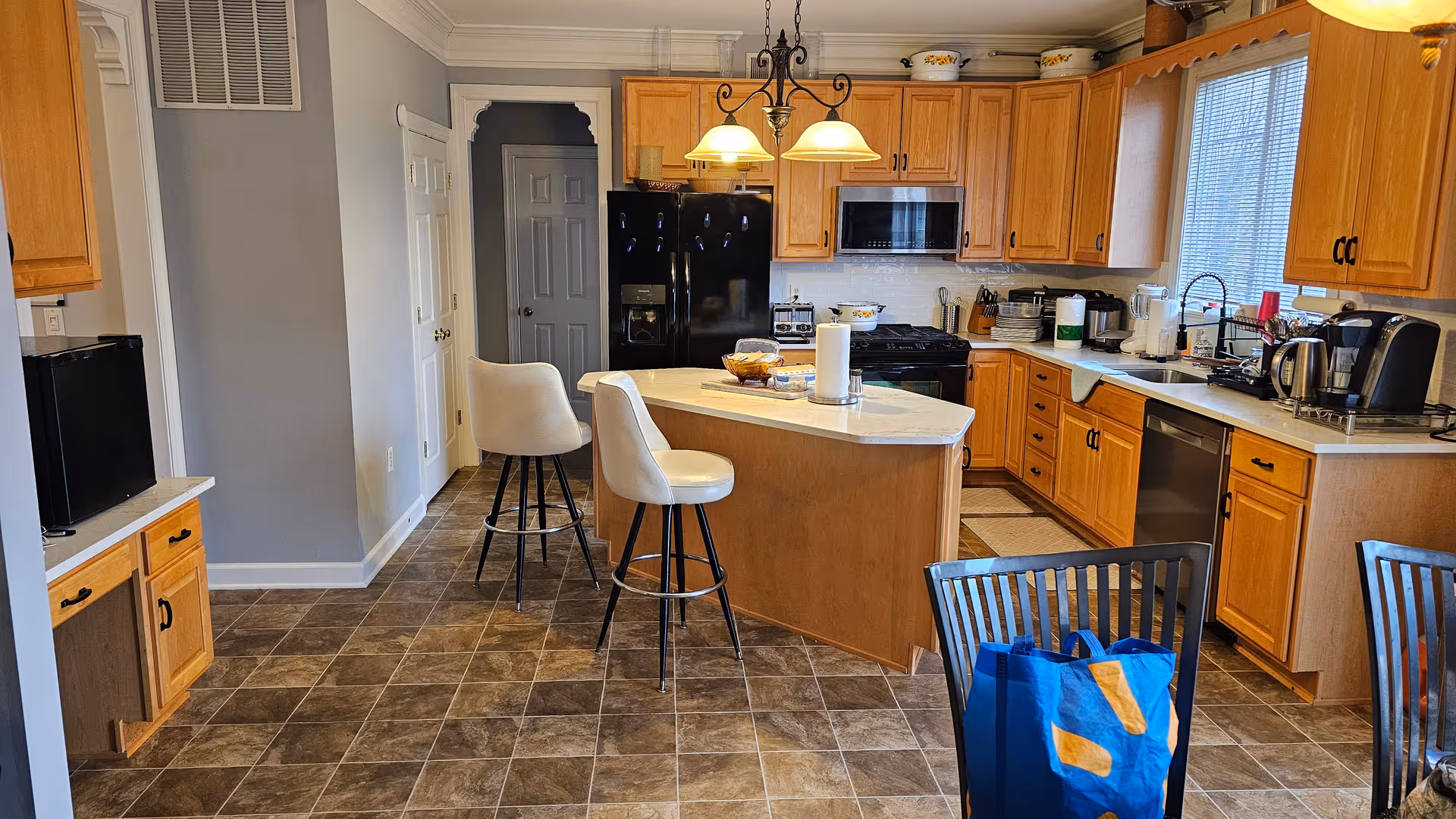 Bright kitchen with central island, light wood cabinets, and modern appliances.