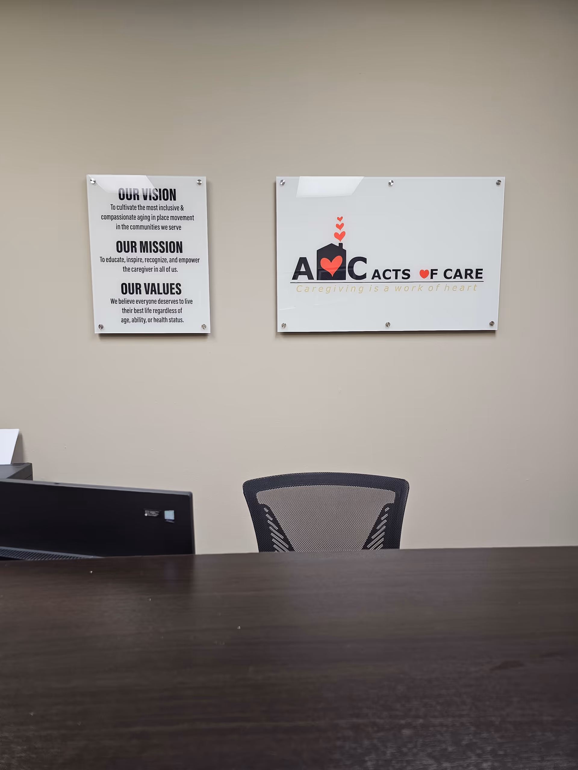 Reception desk with chair and wall plaques labeled Our Vision and Acts of Care
