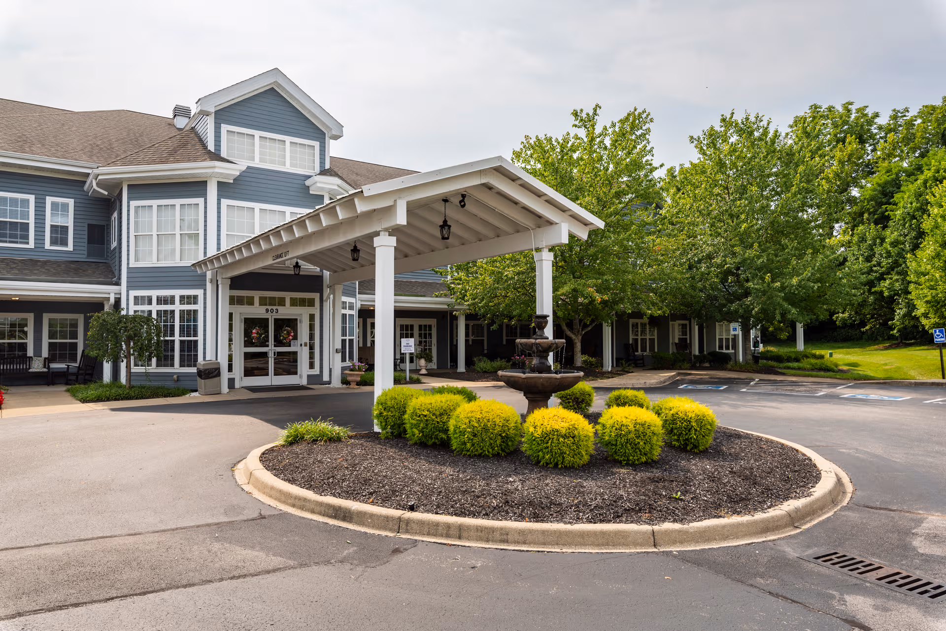 Exterior view of Arcadia Senior Living Louisville entrance with a circular driveway and fountain.