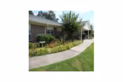 Front exterior of Canterbury Place, a Wesley Living Community, with curved walkway and landscaping.