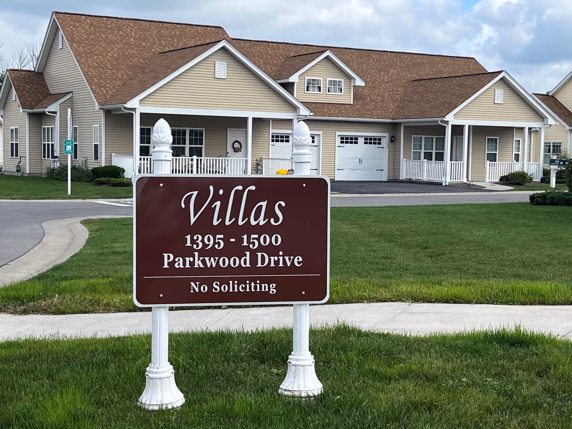 Front exterior of a senior living campus with beige houses and a maroon Villas sign.