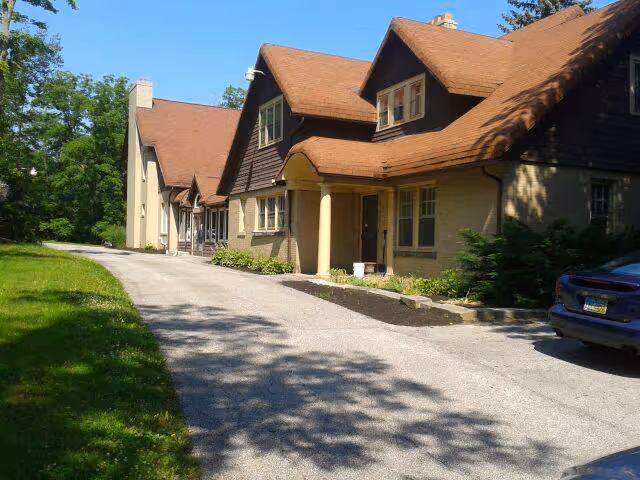 Exterior view of a senior living facility with a driveway and parked car.