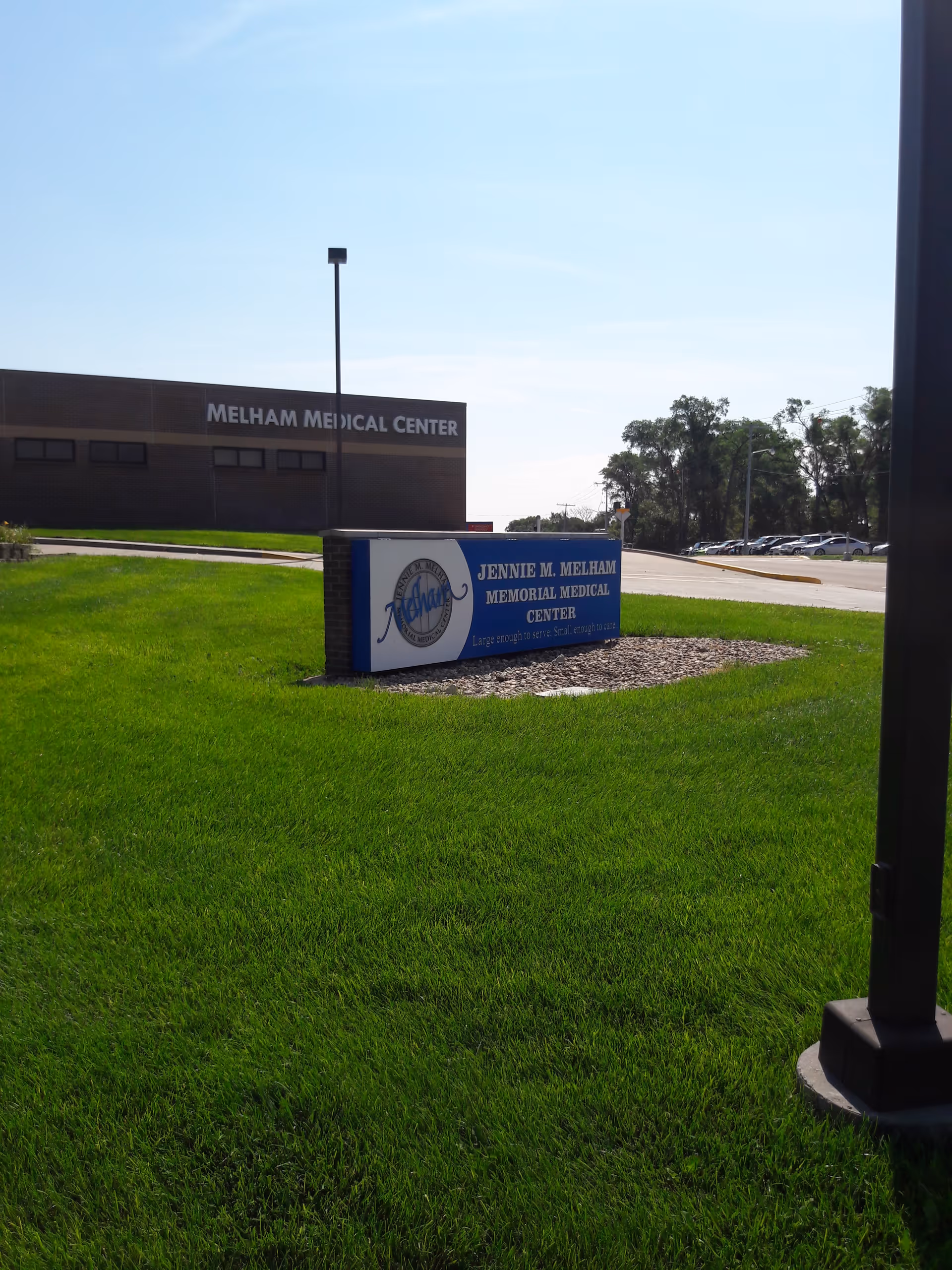 Front view of Jennie M. Melham Memorial Medical Center sign and building on a green lawn.