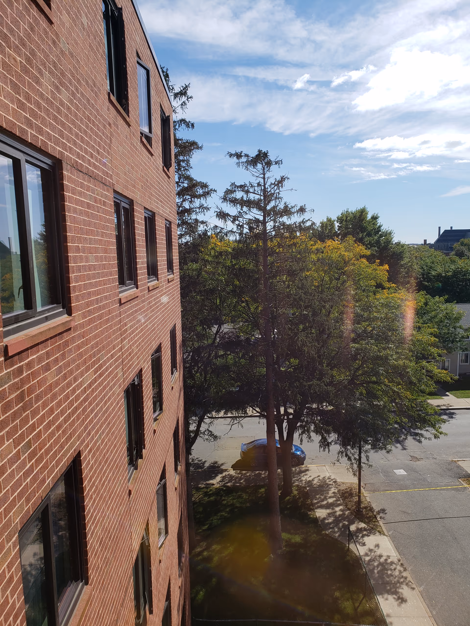 View of a brick senior living building exterior with trees and a street.