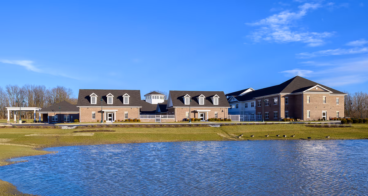 Smith's Mill Health Campus exterior along a pond under a clear blue sky.