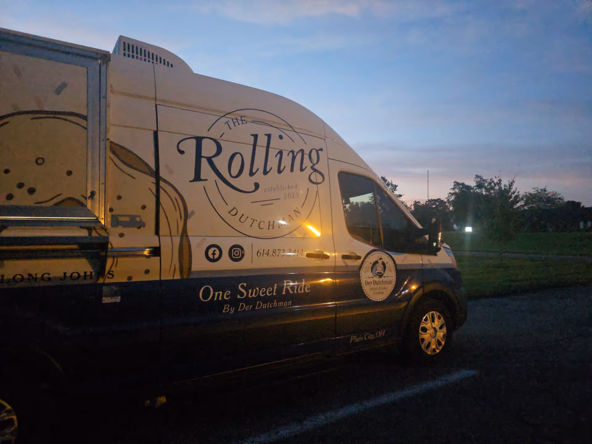 Branded delivery van with The Rolling Dutchman logo parked outdoors at dusk.