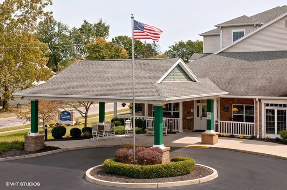 Exterior view of Haven at Lakewood senior living facility with covered entrance and flag