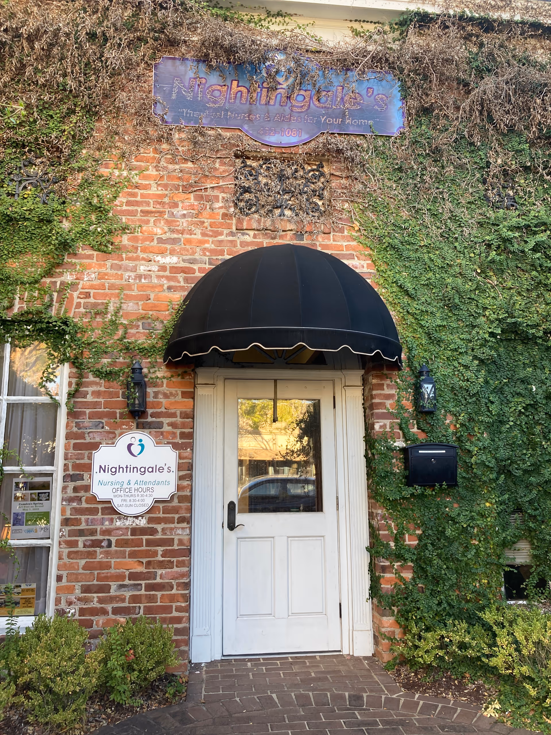Brick building entrance with ivy, black canopy, and Nightingale's Nursing & Attendants signage.