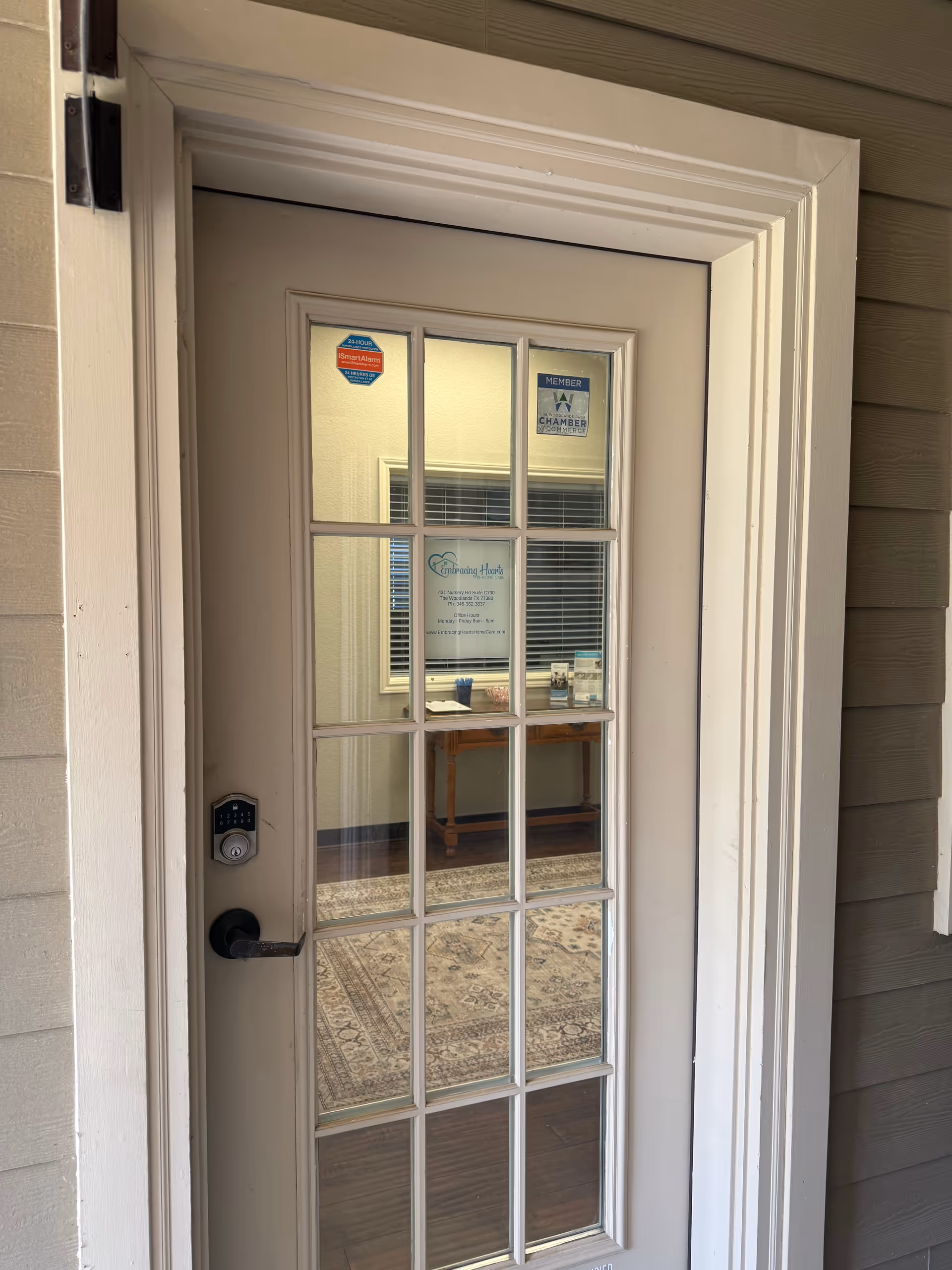 Glass-paneled exterior door with keypad lock, revealing a furnished entry hall inside.