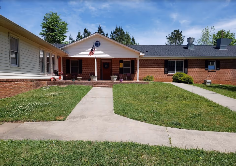 Single-story brick senior living facility exterior with a front entrance and manicured lawn.
