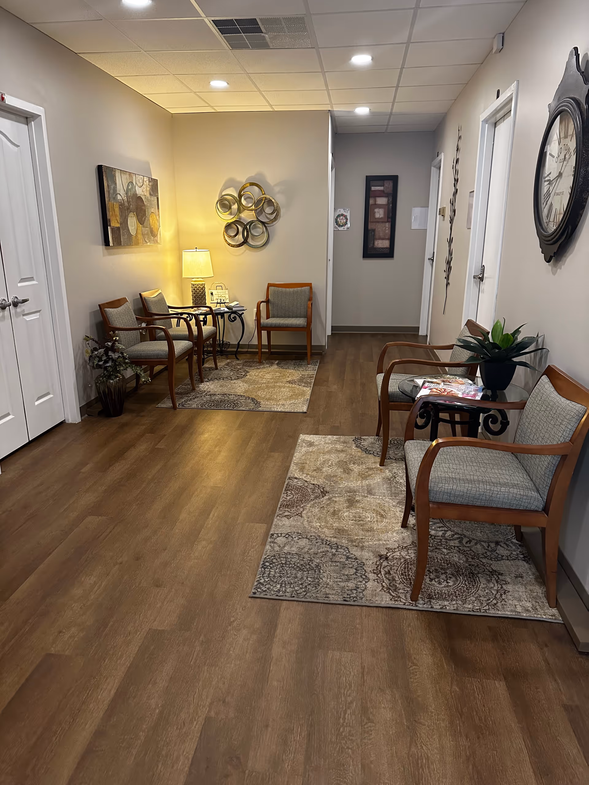 Hallway seating area in a senior living facility with chairs, rugs, and wall art.