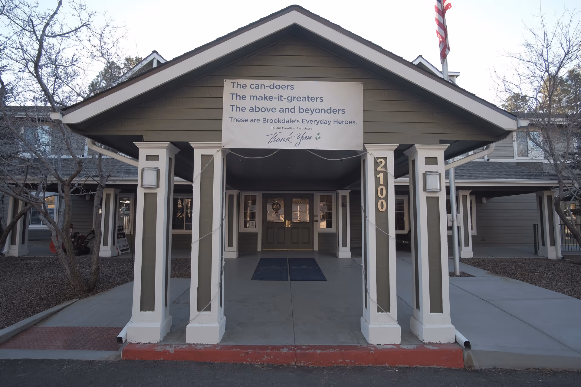Front entrance of Brookdale Flagstaff senior living, covered porte-cochère with banner above doors.