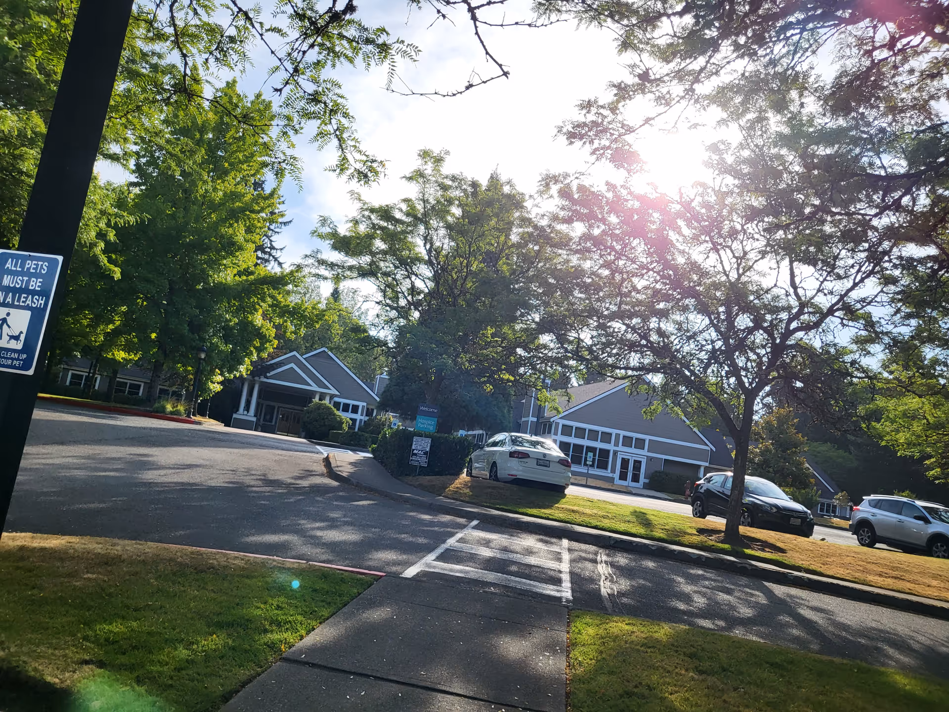 Exterior view of EvergreenHealth Hospice Services building, with driveway, parking, and leafy trees