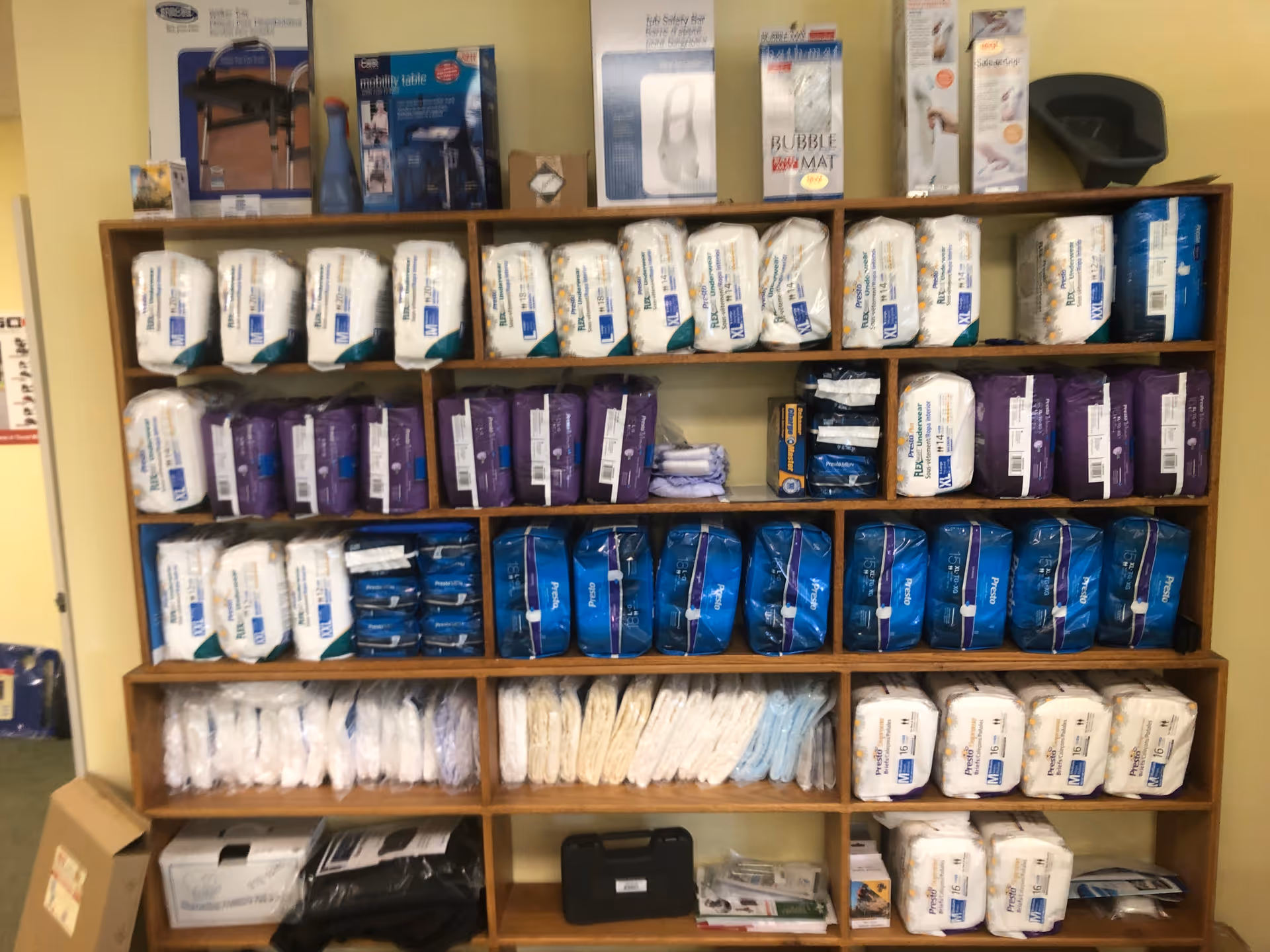 Shelves stocked with assorted incontinence products and medical supplies in a facility storage area.