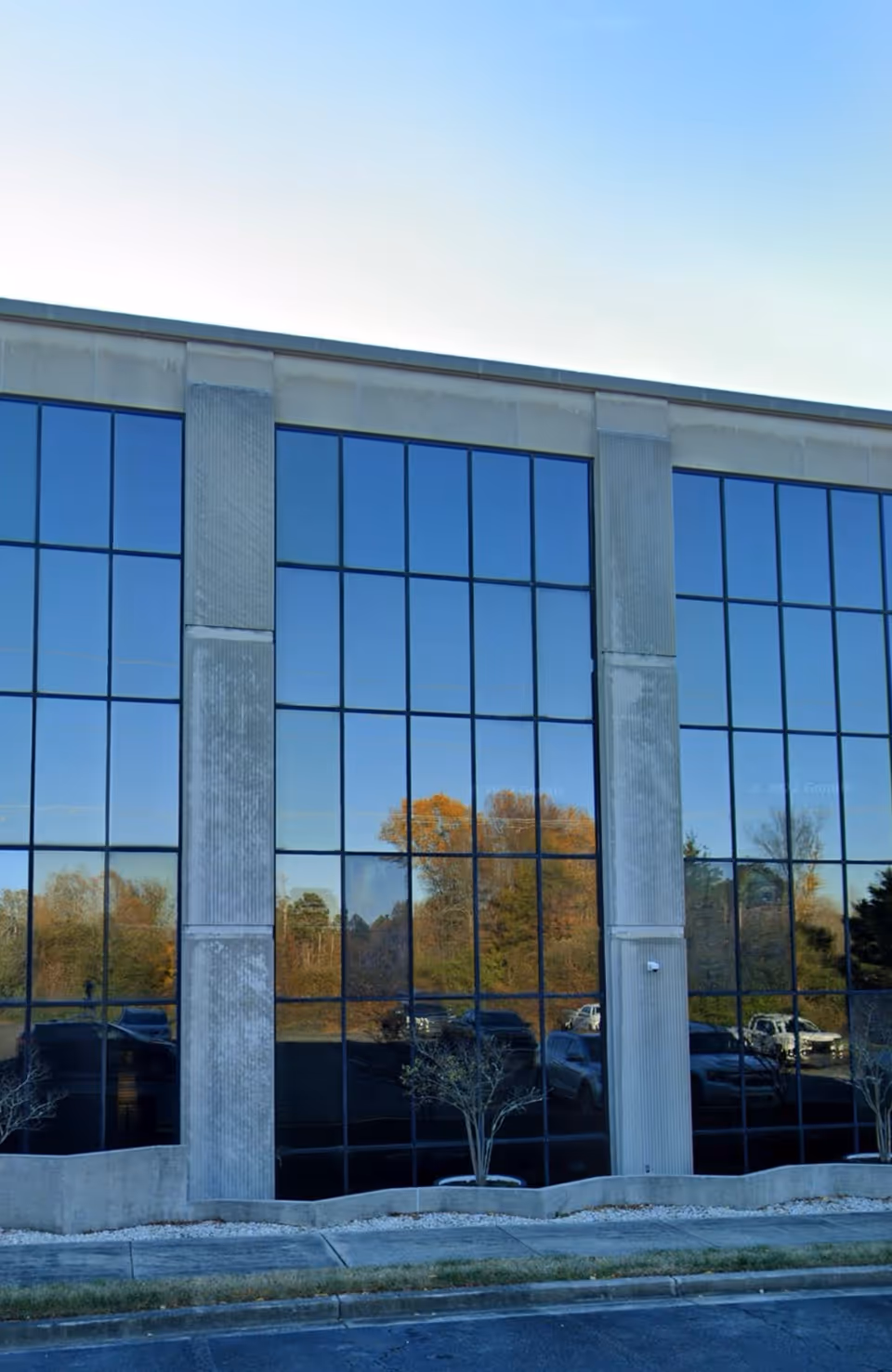 Exterior view of a modern glass-front building with tall, reflective windows and concrete columns.