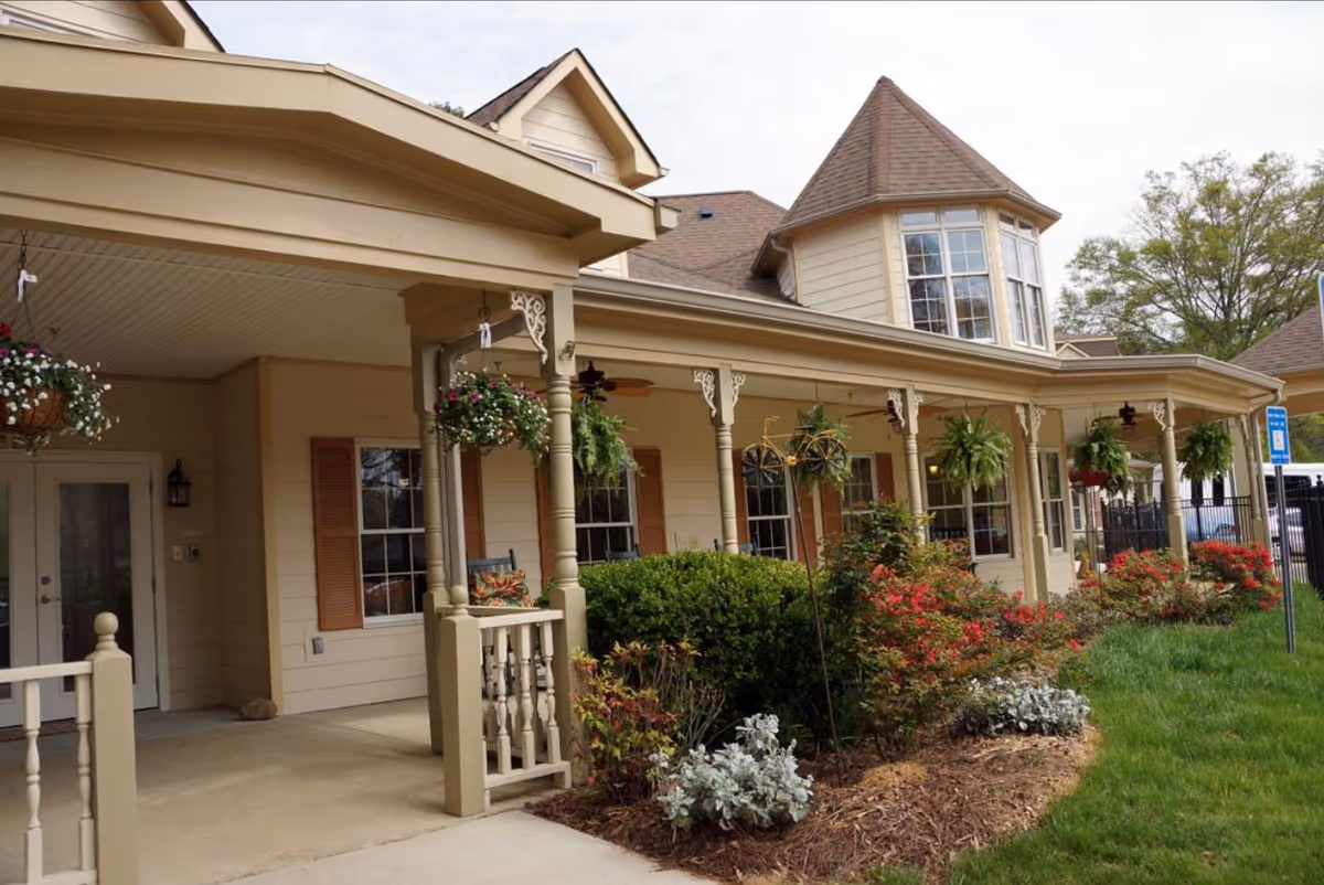 Exterior view of Highlands Senior Living Norcross with a front porch and hanging plants.