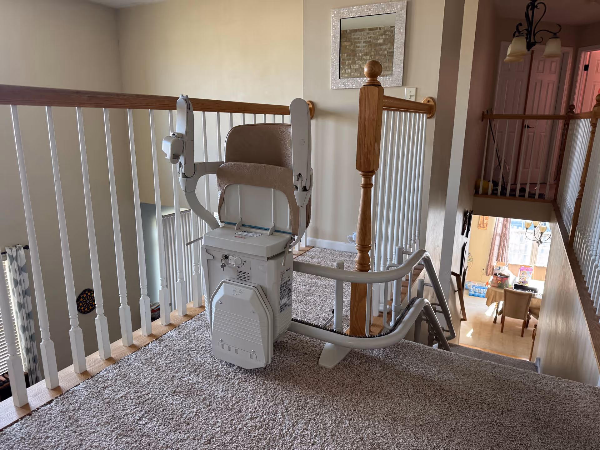 Indoor stair landing featuring a chairlift beside a wooden railing on carpeted stairs.