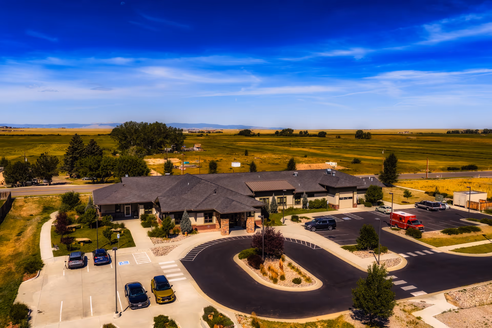 Aerial view of Hospice of Laramie, a single-story facility with circular driveway, parking, and surrounding fields.