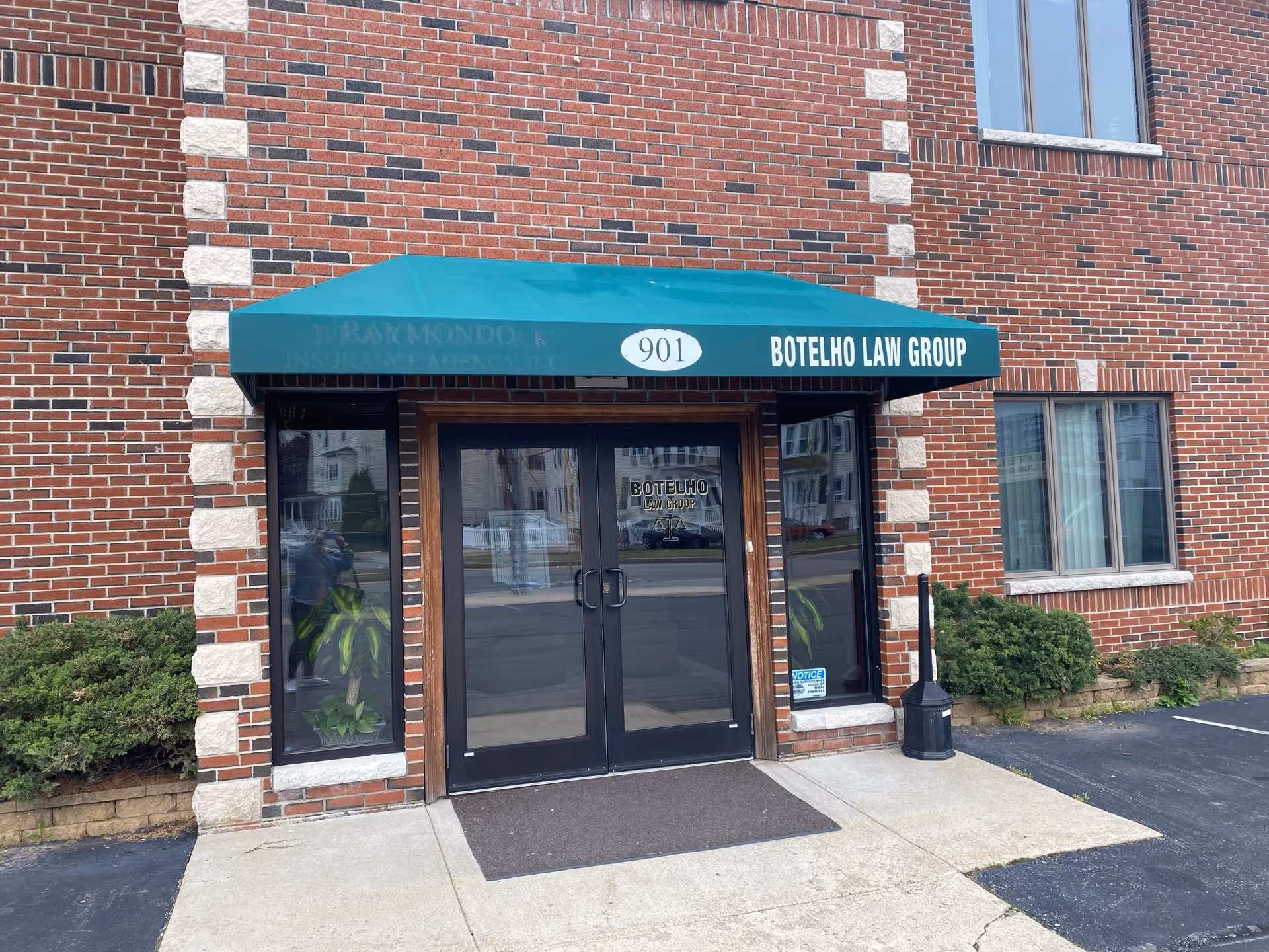 Brick building entrance with teal awning and glass doors labeled Botelho Law Group