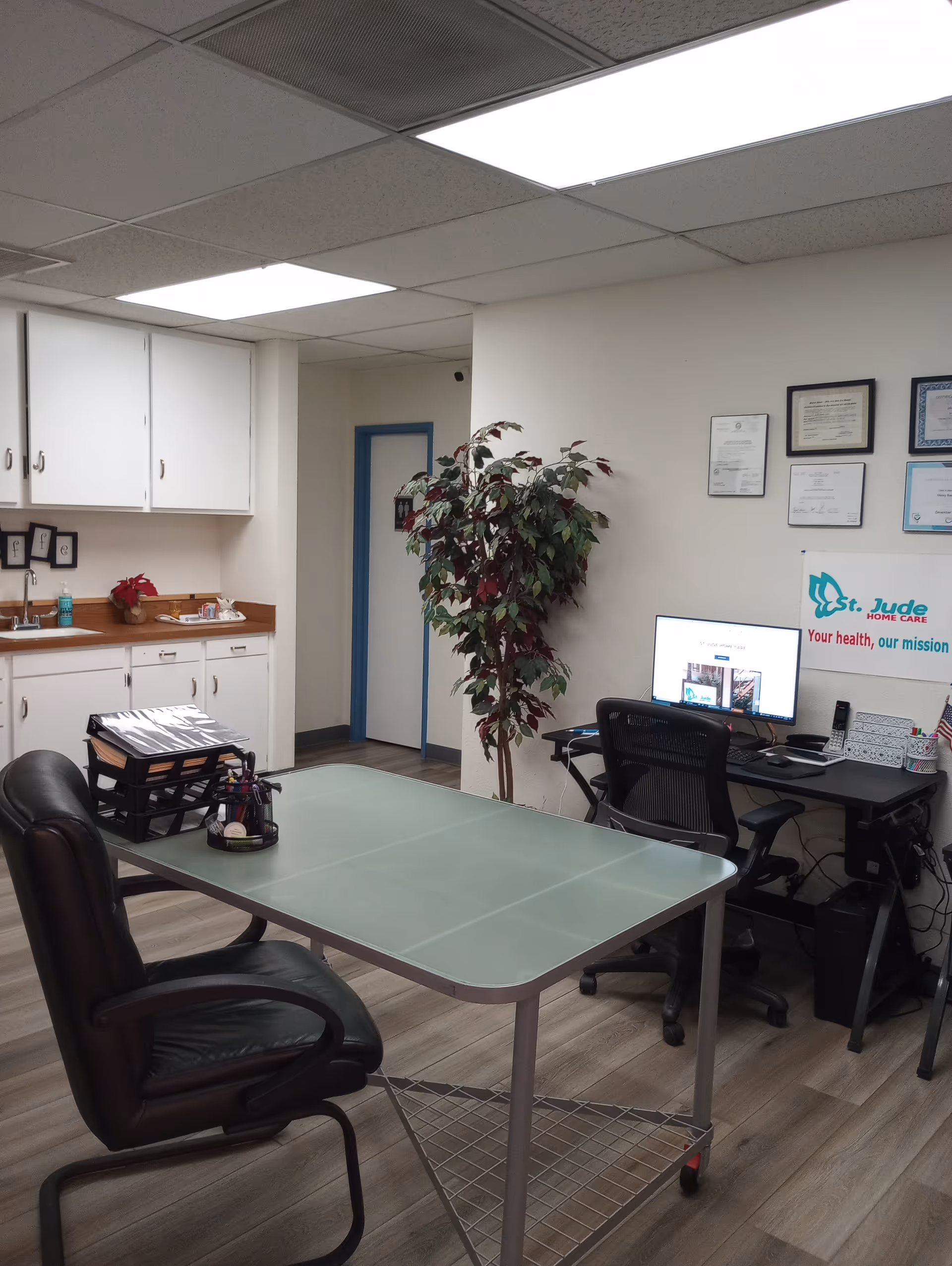 Office area in a care facility with desk, computer, plant, and cabinets.