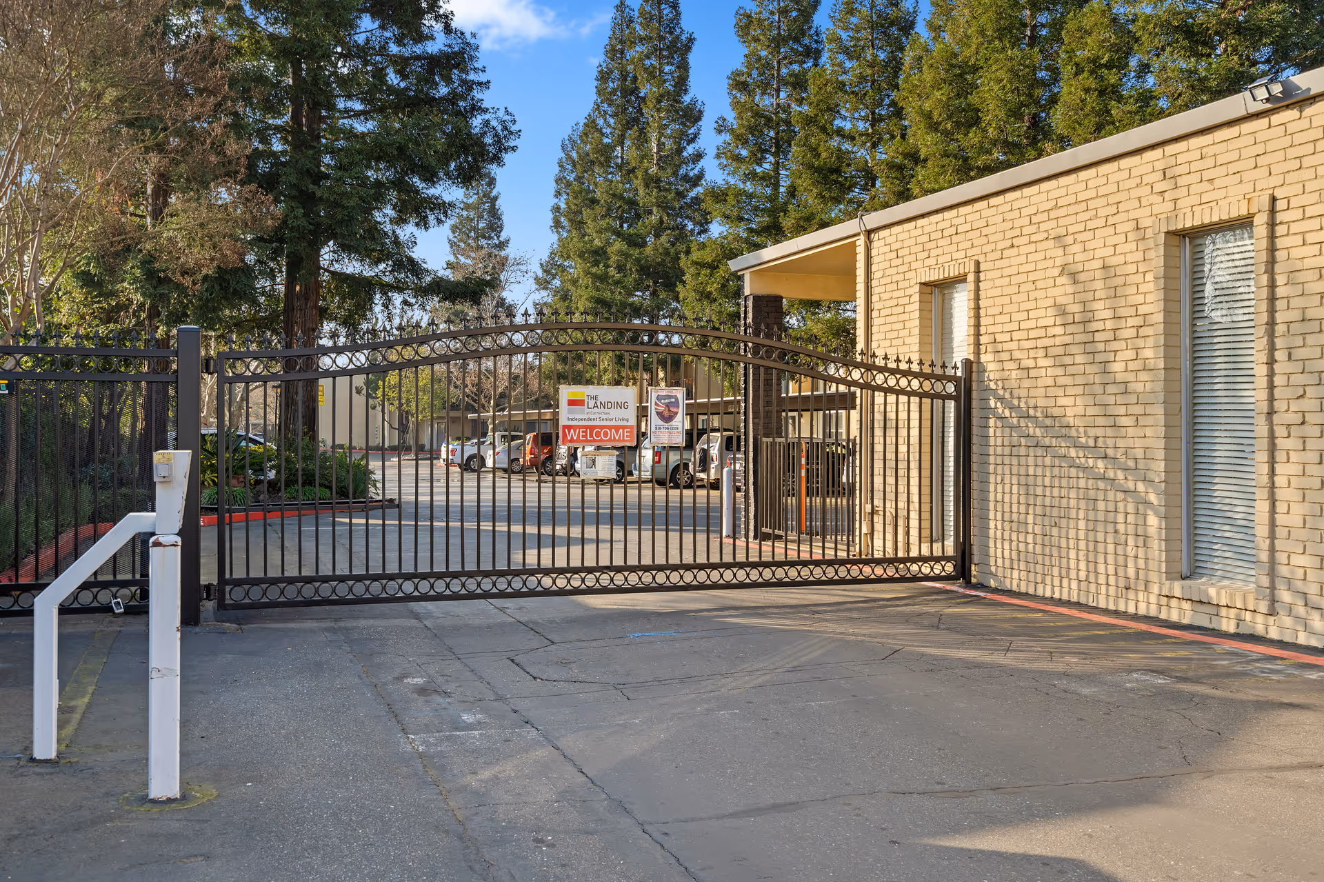 Gated entrance to The Landing at Carmichael exterior with brick building and surrounding trees.
