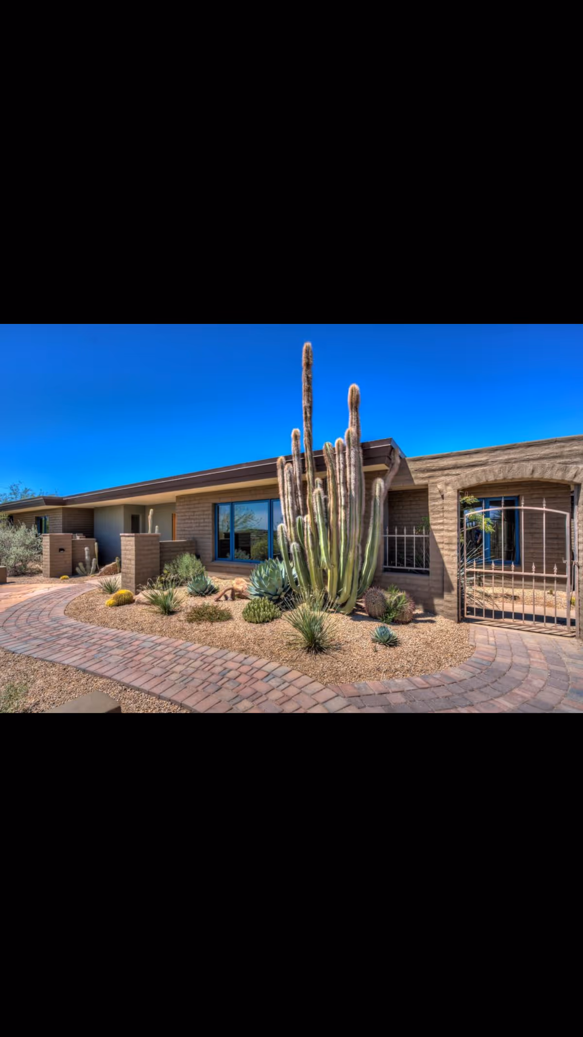 Desert landscaping frames a brick exterior building with a curved brick walkway.