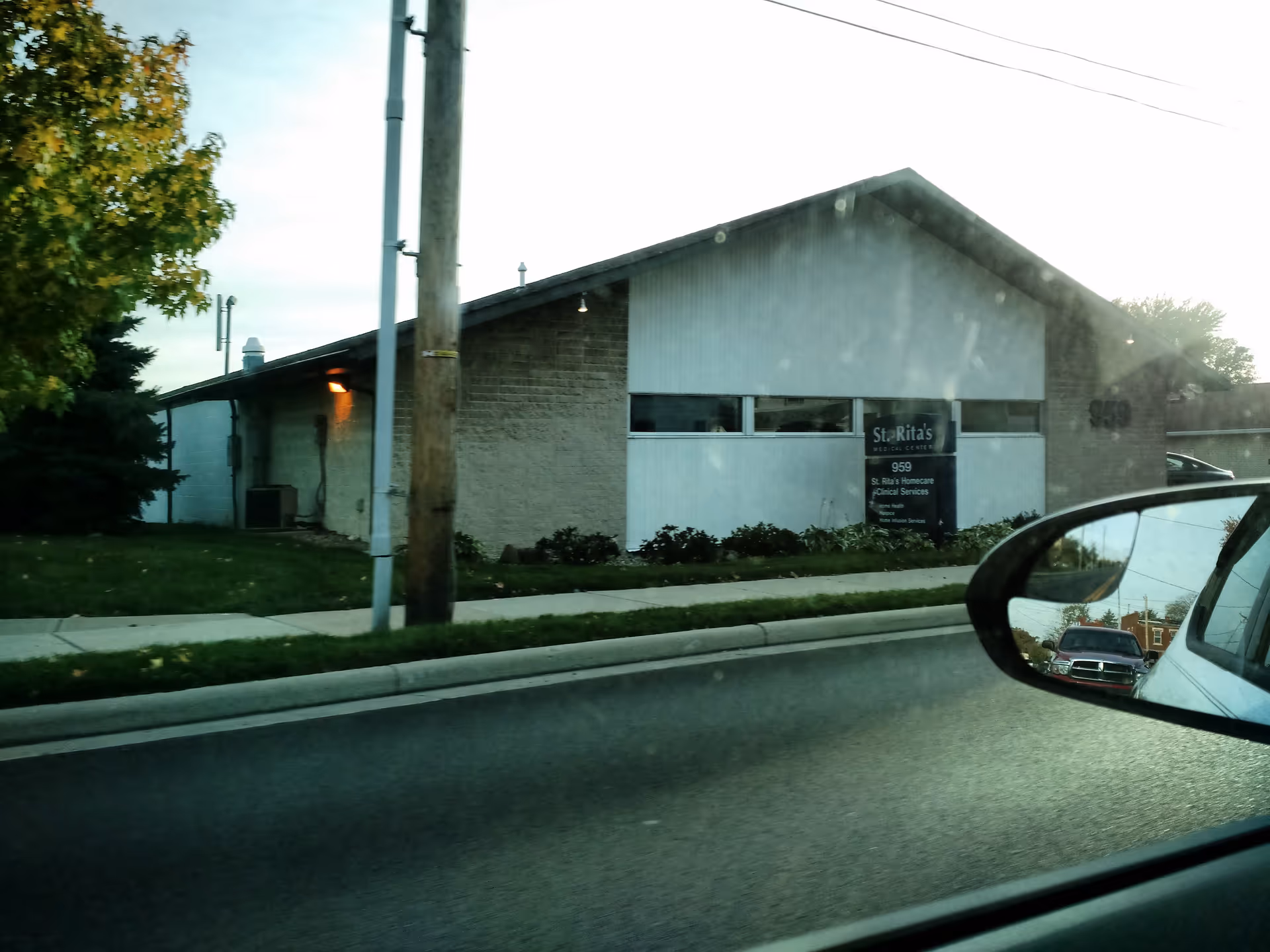 Exterior view of a single-story building with a sign and street in foreground