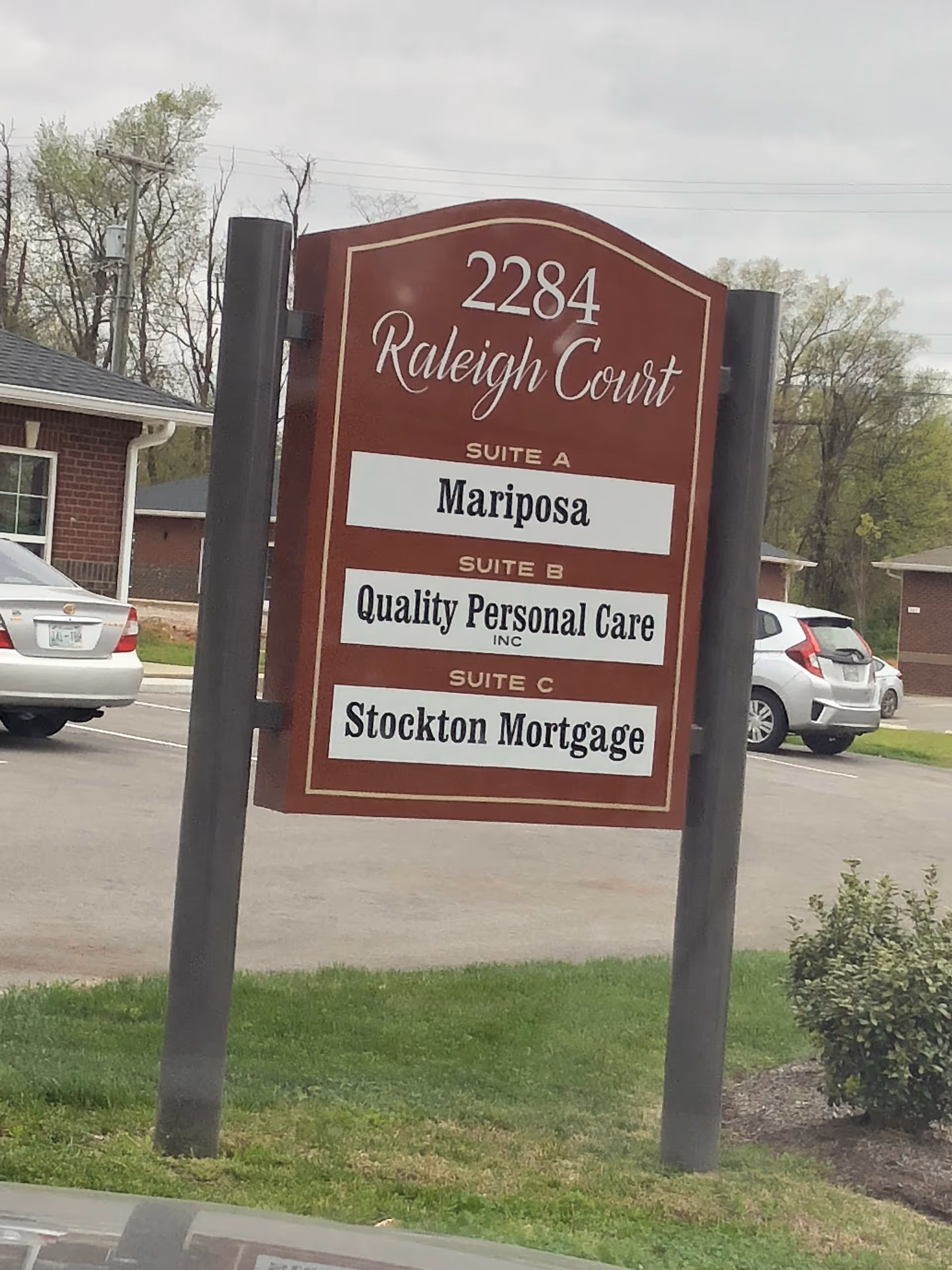 Tall red signboard lists suites at Raleigh Court, including Mariposa and Quality Personal Care.