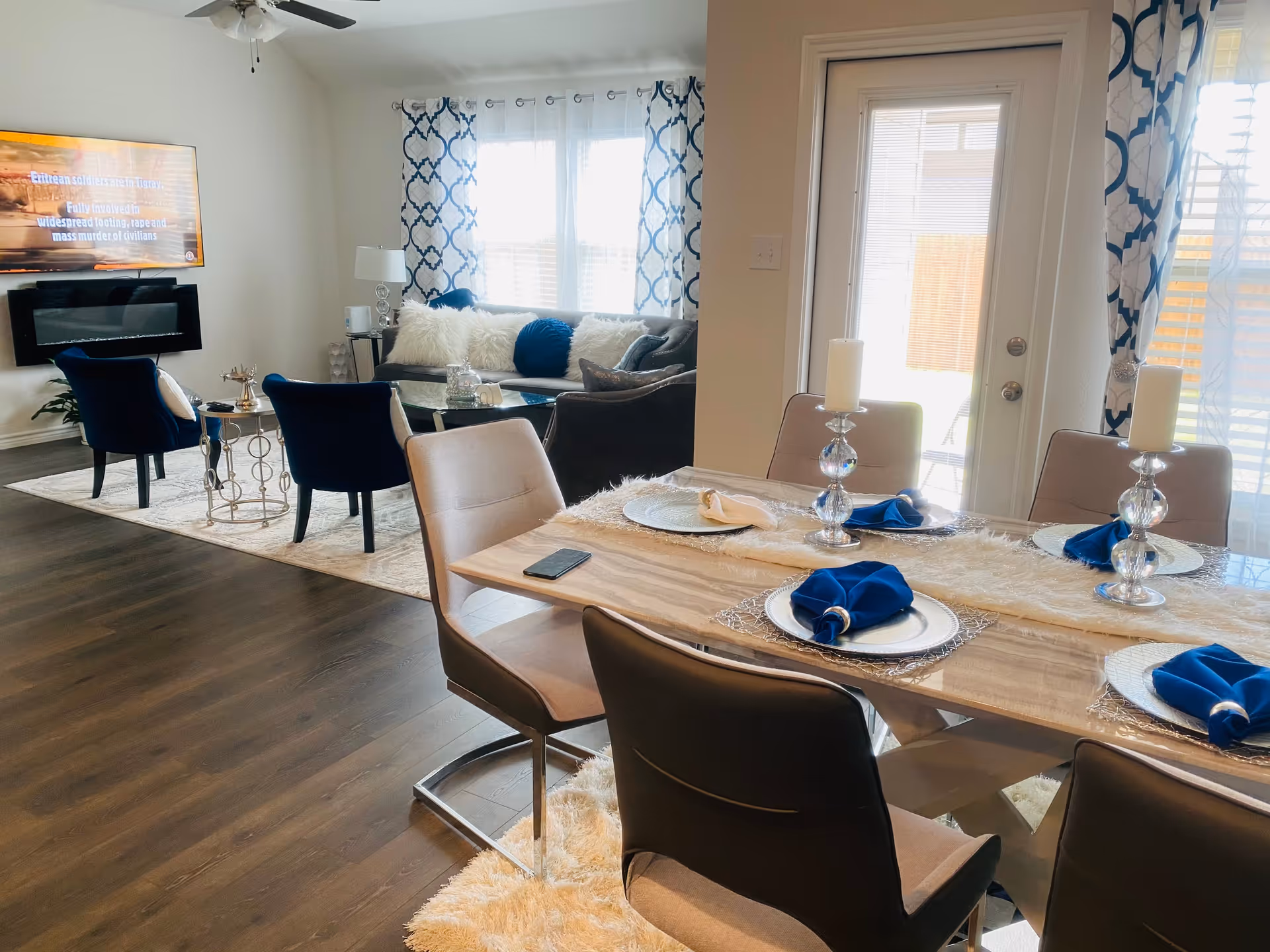 Open-plan dining and living area with a wooden dining table and blue-accent décor.