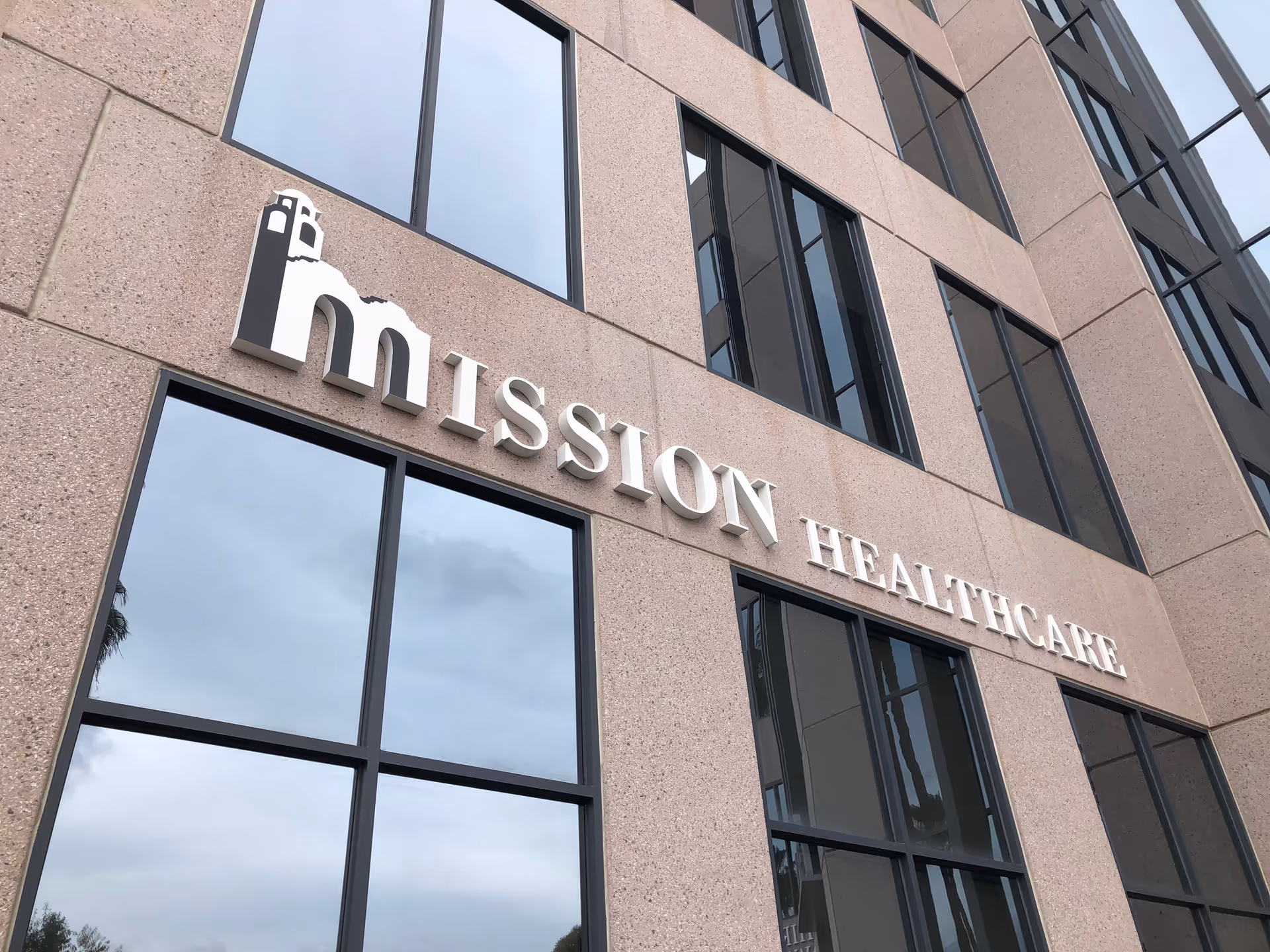 Facade of Mission Healthcare building with large windows and a prominent sign.