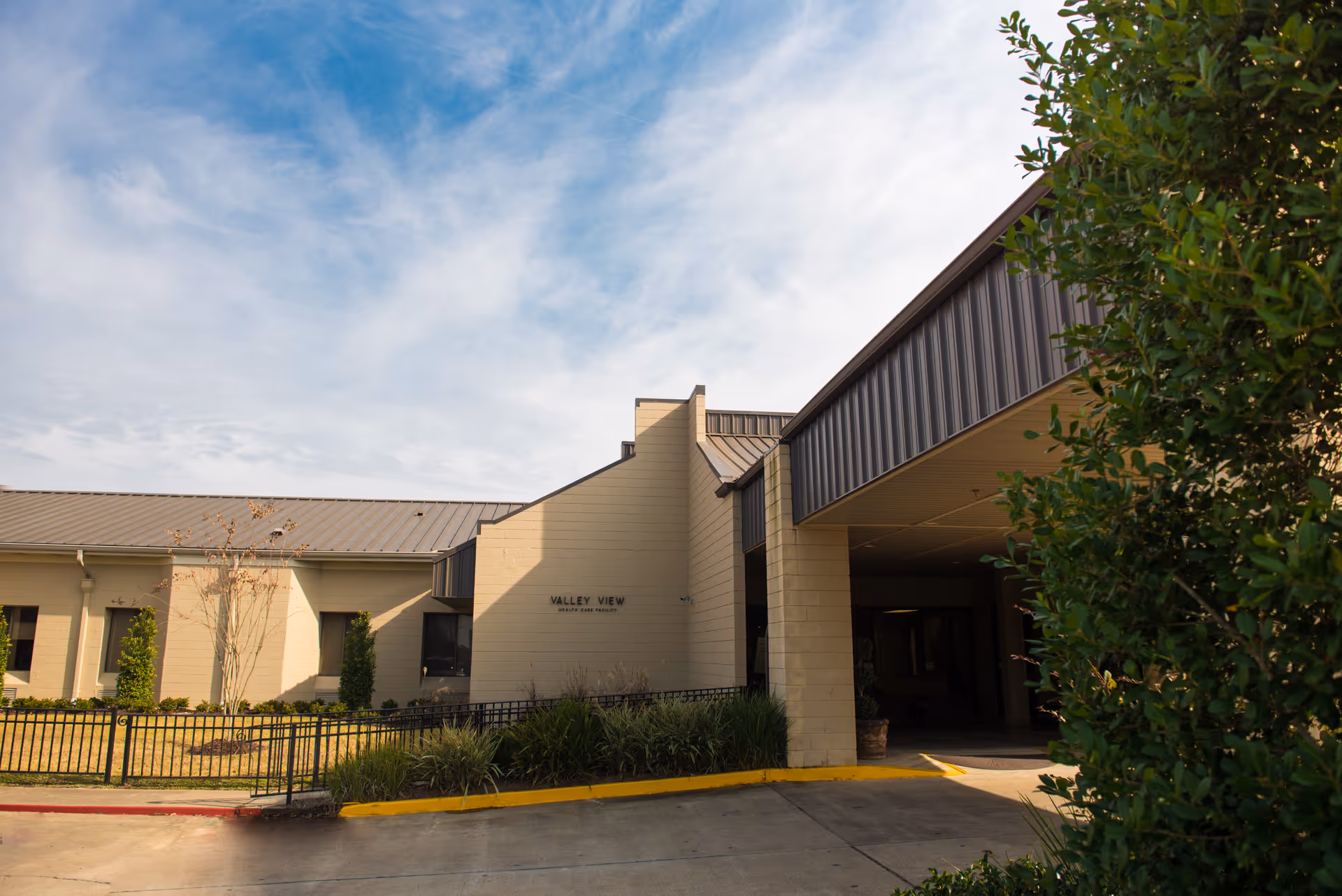 Exterior view of Valley View Health Facility front entrance with landscaping and blue sky.