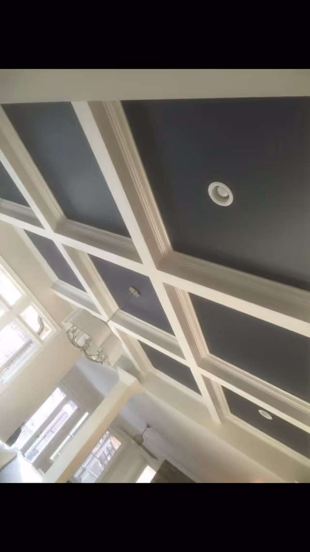 The ceiling features navy blue coffered panels with white trim and chandeliers in a bright interior.