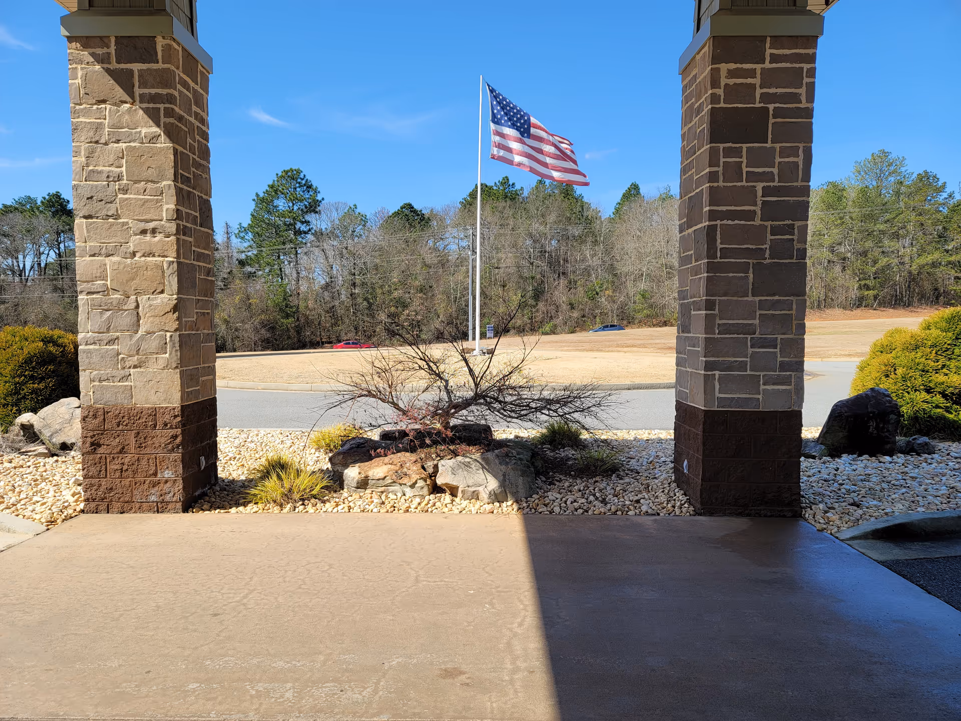 Stone pillars frame a covered entrance with an American flag and landscaped ground.