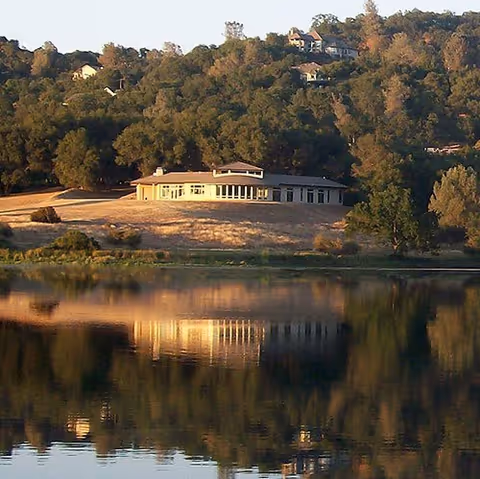 Lakefront Oaks Estate exterior sits by a lake with trees and reflected water.