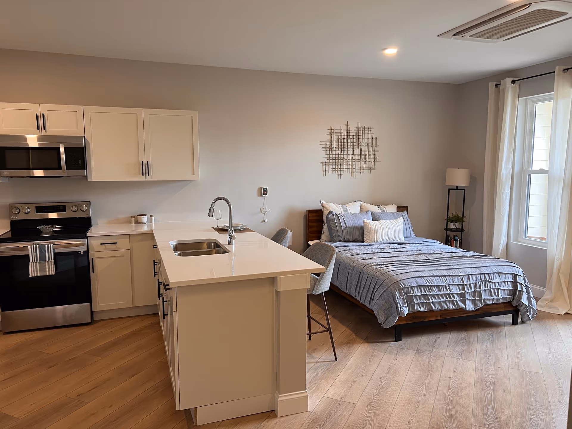 Open-concept kitchen and bedroom in a modern unit with an island and bed.