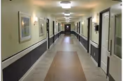 Interior hallway at New Hope Manor, long, well-lit, with framed art and doors.